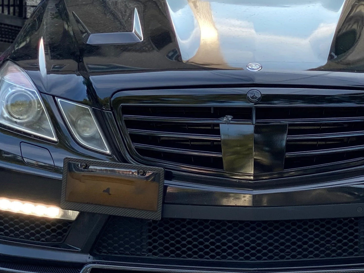 Carbon fiber license plate frame with smoked window installed on black luxury vehicle front bumper